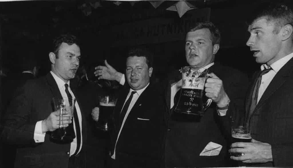 Archive photo from a beer karczma: four participants holding tankards under a banner