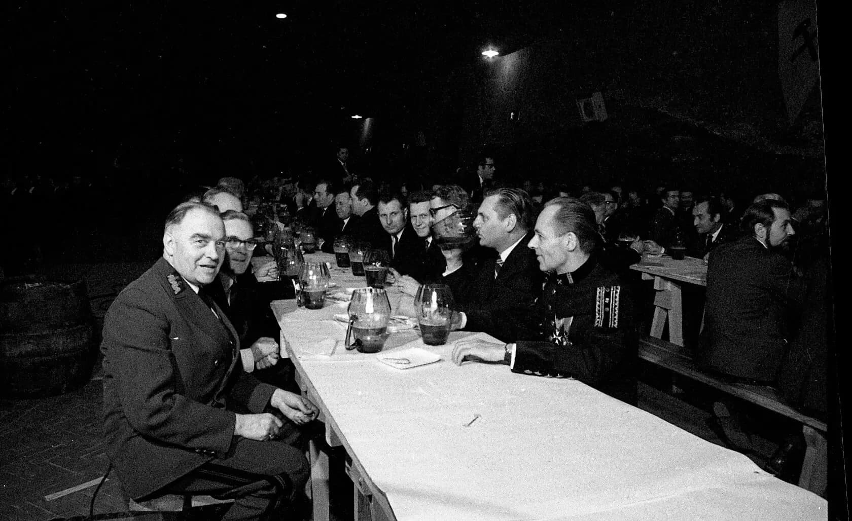 Archive photo from a beer karczma: a long table of participants in ceremonial uniforms and evening dress