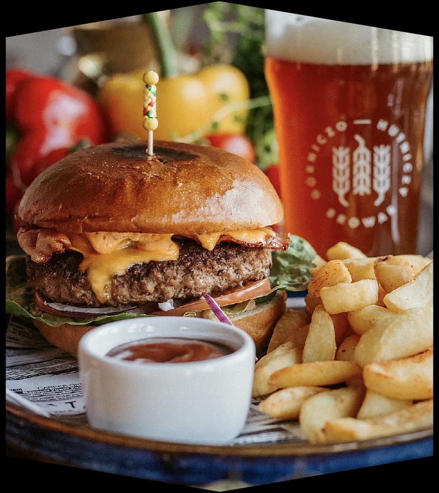 A burger and fries on a Bistro Studio plate, with a glass of BGH beer alongside