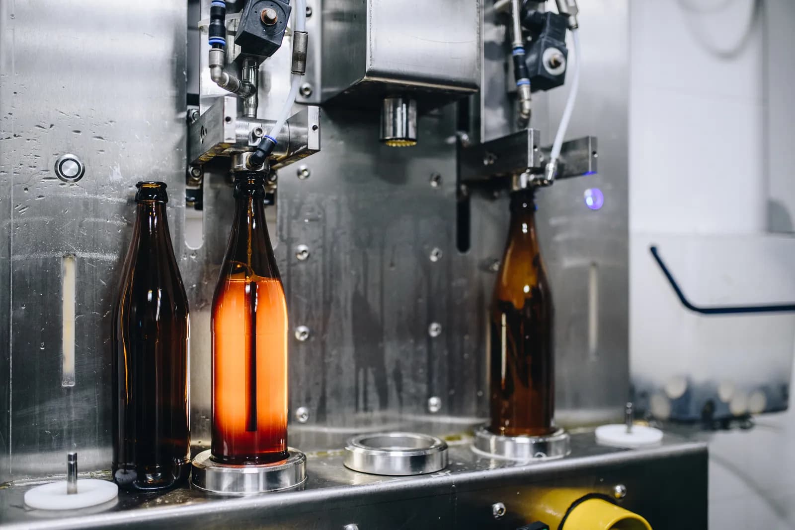 Three bottles at the filling station, the middle one filled with beer
